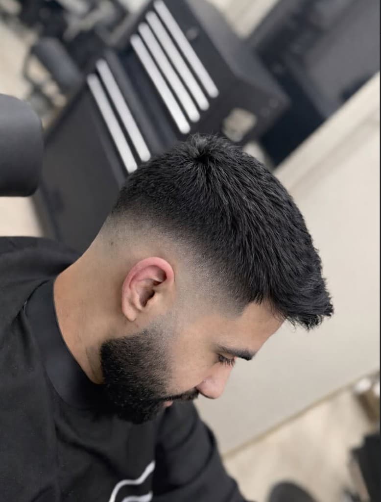 High skin fade met strakke baardlijn en nek, profiel in de salon